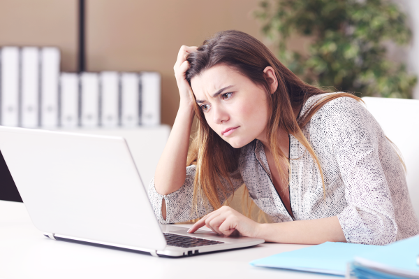 young woman with confused look working on a laptop